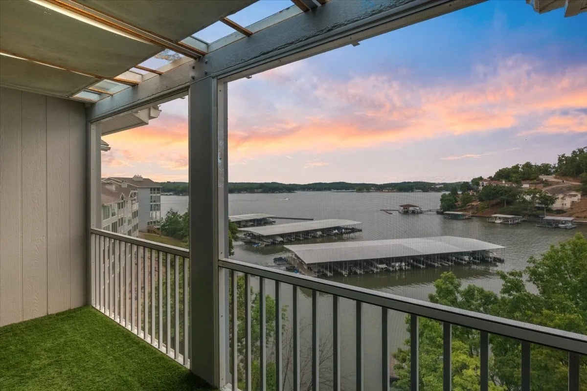 This view image shows a breathtaking lake scene at sunset, as seen from a balcony with a classic railing. The tranquil waters and colorful sky evoke the perfect backdrop for drinks, conversation, or quiet reflection before heading out for an evening of local nightlife.
