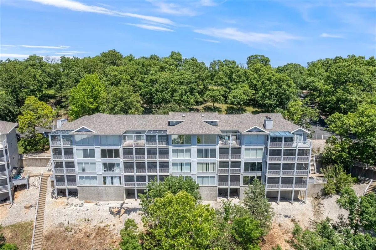 A serene view of the multi-story condo building surrounded by greenery, with balconies visible. The image highlights the proximity to nature and outdoor spaces for both pets and owners to enjoy, while also nodding to the comfort of returning home.