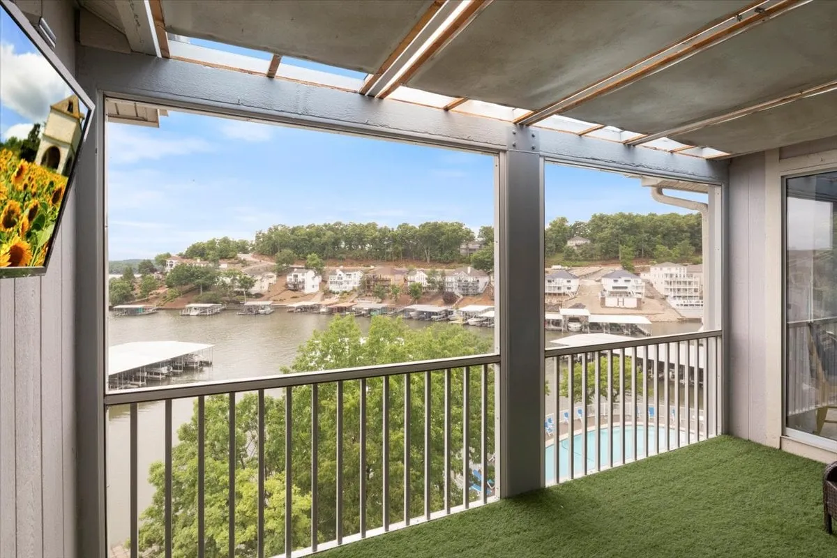 A serene exterior shot overlooking the lake from a balcony, with greenery framing the peaceful water view. The balcony railing is visible, suggesting a comfortable spot for relaxation or contemplation.